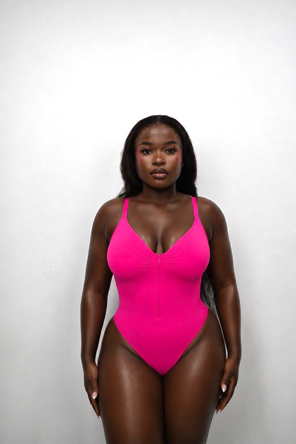 Front view of a model wearing the pink IYRA Shape zip bodysuit.